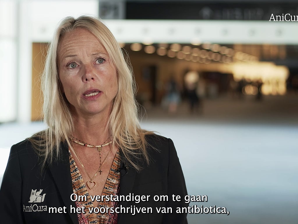 Een persoon met blond haar en een zwarte jas.