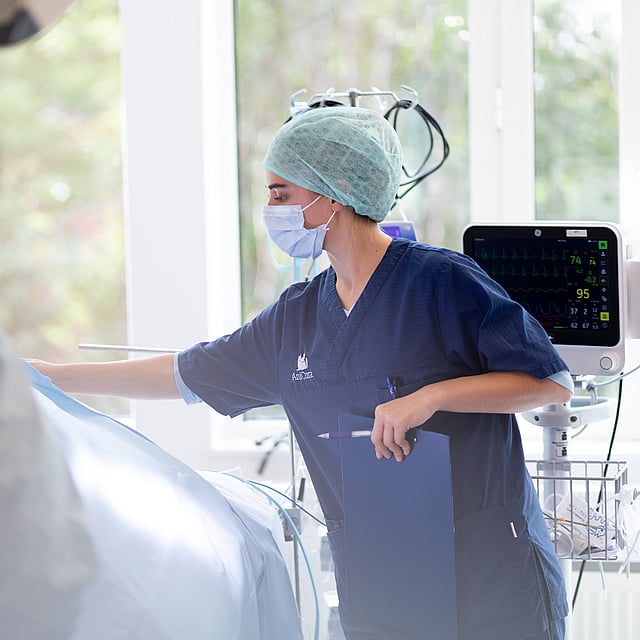 Een persoon die chirurgische scrubs en een masker draagt.