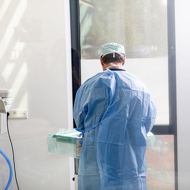 Een persoon in een blauwe jurk en pet die zich in een kamer bevinden.