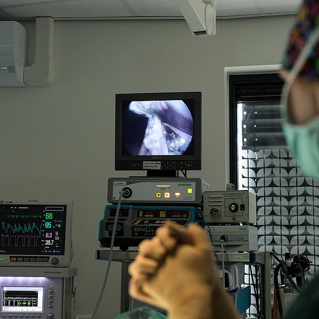 Een persoon met een masker die naar een televisie kijkt.