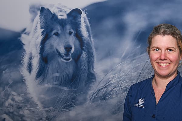 Een persoon die glimlacht voor een foto van een hond.