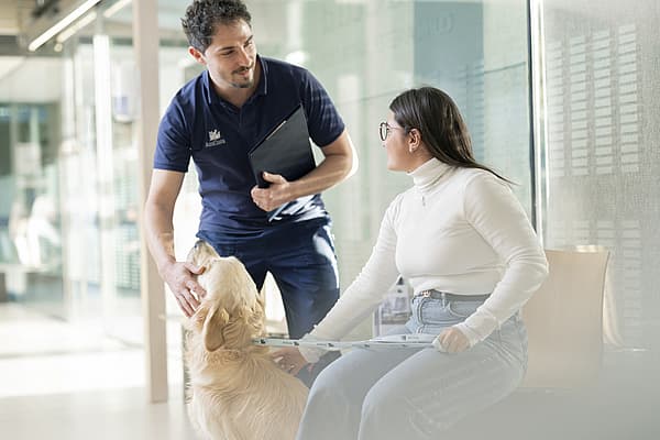 Een persoon en persoon zittend op een bank met een hond.
