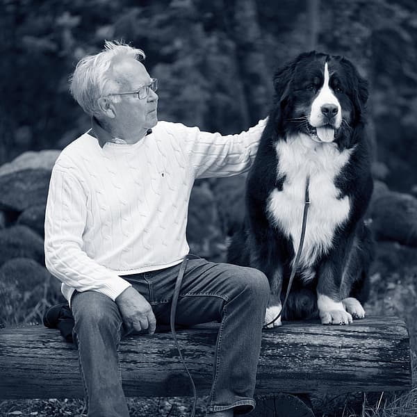 Een persoon die op een boomstam met een hond zit.