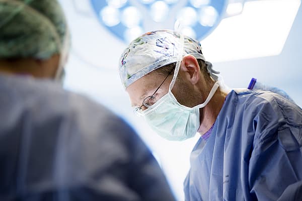 Een arts die chirurgische scrubs en masker draagt.