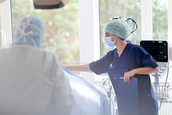 Een persoon die chirurgische scrubs en een masker draagt.