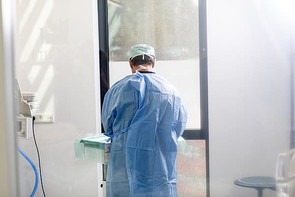 Een persoon in een blauwe jurk en pet die zich in een kamer bevinden.