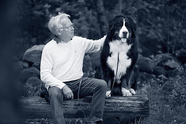 Een persoon die op een boomstam met een hond zit.