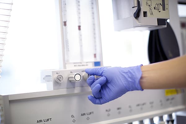 Een persoon die een handschoen draagt en een draaiknop aanpast.