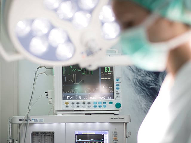 Een persoon met een masker en een chirurgisch masker in een operatiekamer.