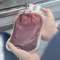 Een persoon die een zak bloed vasthoudt.