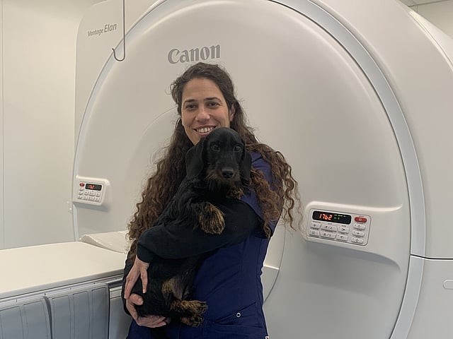 Een persoon die een hond vasthoudt in een kamer met een grote machine.