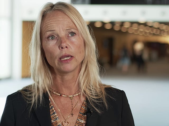 Een persoon met blond haar en een zwarte jas.