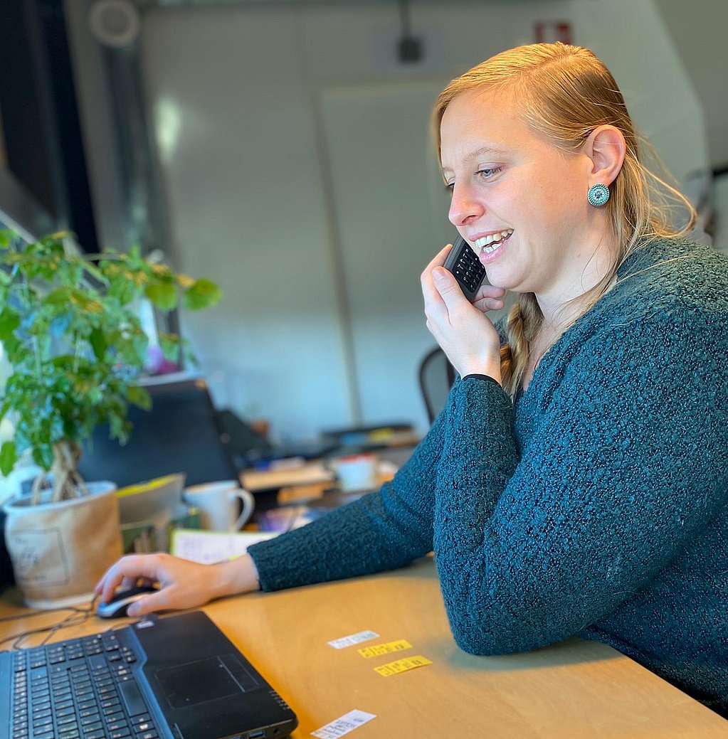Een persoon die aan een bureau zit te telefoneren.