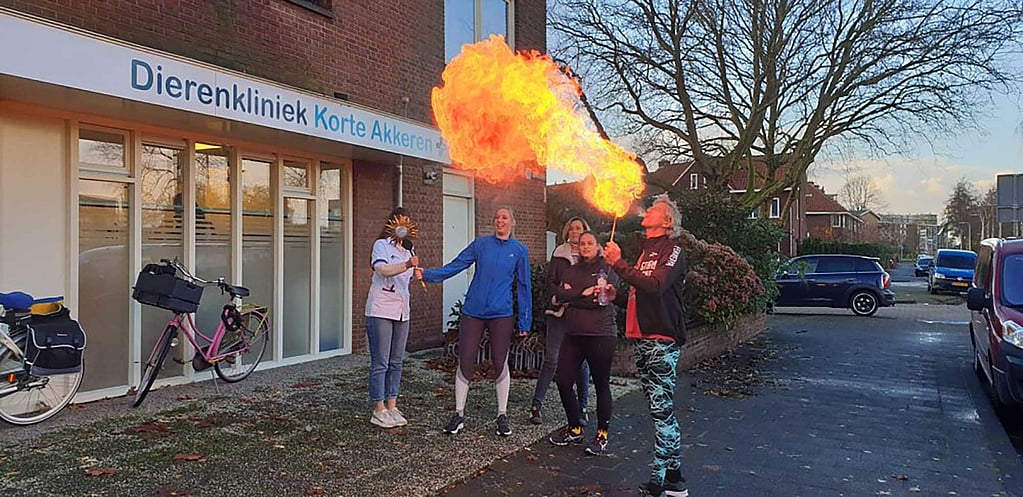 Een groep mensen buiten bij een gebouw met een vuur.