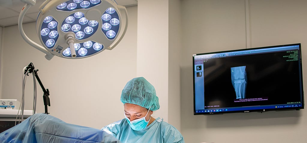 Een persoon in scrubs en chirurgische muts.