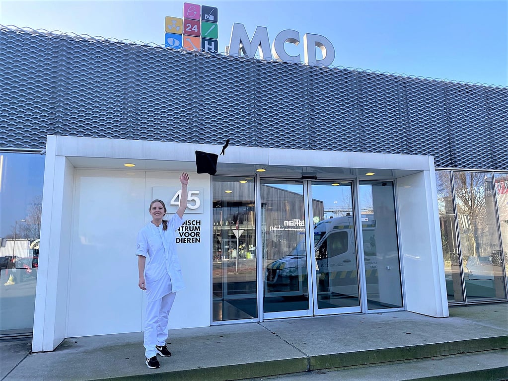 Een persoon in witte jumpsuit die voor een gebouw springt.