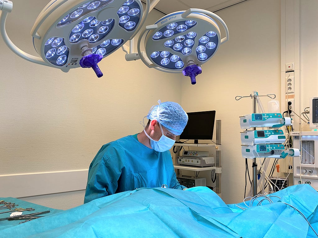 Een persoon in een operatiejas en masker.