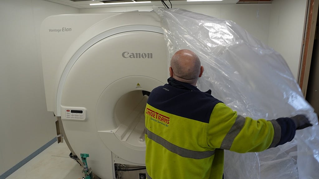 Een persoon die naast een grote machine staat.