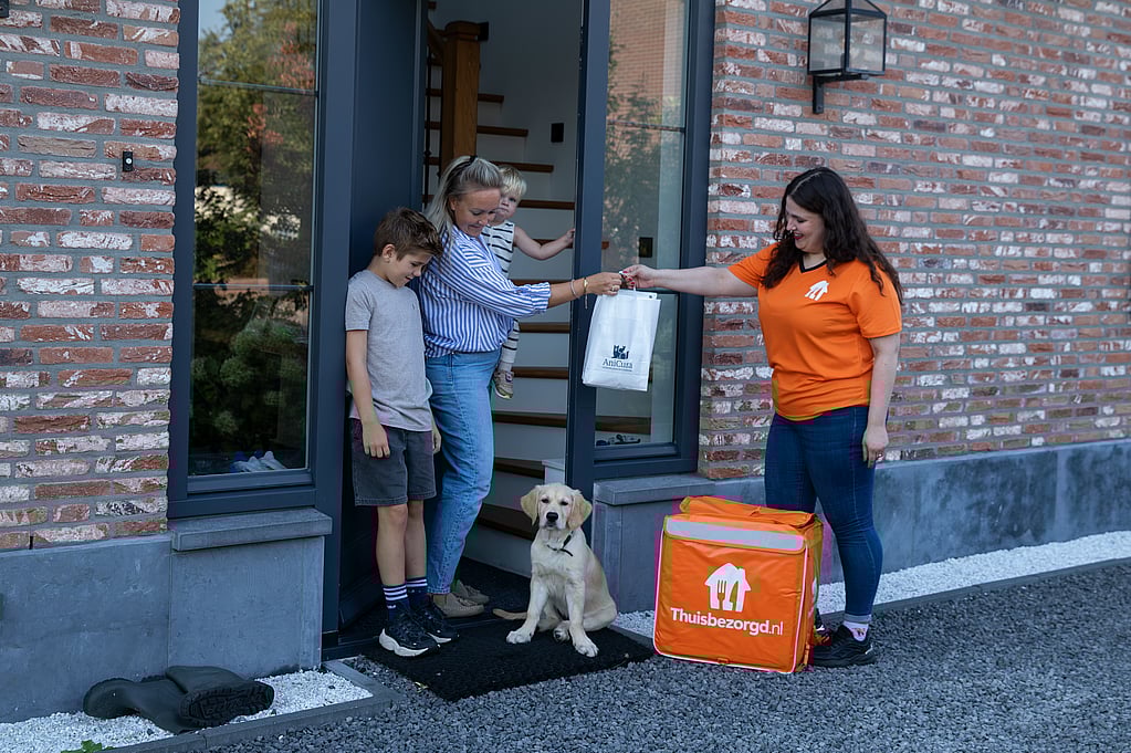 Een persoon die een tas aan een hond overhandigt.