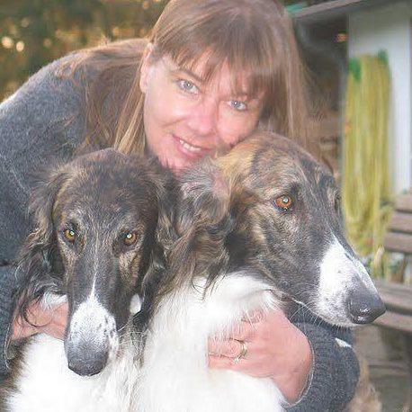 Een persoon die twee honden vasthoudt.